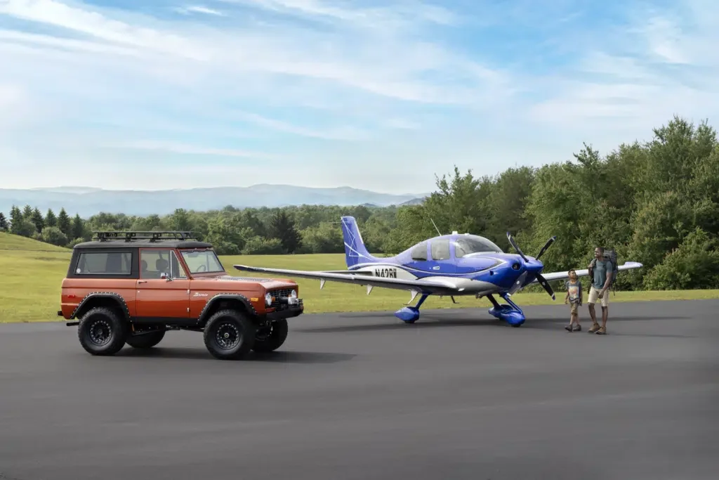 suv and blue cirrus plane side by side with father and son